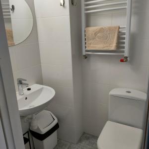 a white bathroom with a sink and a toilet at Pokoje Klonowa in Kołobrzeg