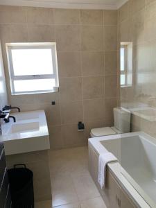 a bathroom with a tub and a sink and a window at 7 on Sachs in Cape Town