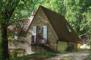 uma pequena casa de pedra com uma janela e uma varanda em Roquecombe em La Roque-Gageac