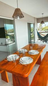 uma mesa de madeira com pratos e copos em Resort Villa das águas praia do saco em Estância