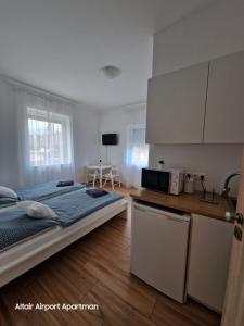 a bedroom with a bed and a kitchen with a microwave at Altair Airport Apartman in Vecsés