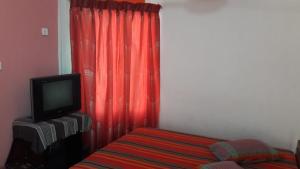 a bedroom with a red curtain and a tv at Hotel Mount in Kurunegala