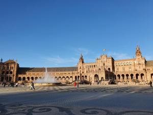 a large building with a fountain in a courtyard at Hostal Puerta Carmona in Seville