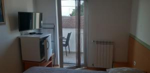 a bedroom with a flat screen tv and a balcony at Apartments & Rooms Villa Adamović in Umag