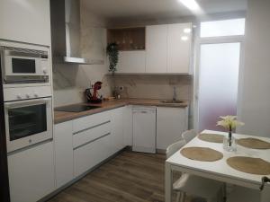 a kitchen with white appliances and a table with chairs at Balcón del Cardenal in Baeza