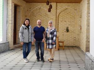 two men and a woman standing on a patio at OLD SAFARI HOTEL make yourself at home in Bukhara