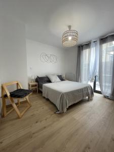 a bedroom with a bed and a chair and a chandelier at Charmant T2, parking privé in Argelès-Gazost
