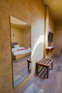 a mirror in a room with a bed and a bench at Bait Ali in Wadi Rum