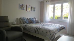 una camera da letto con un letto, una finestra e una sedia di B&B Andrey a Marly-le-Grand