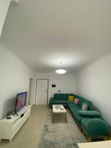 ein Wohnzimmer mit einem grünen Sofa und einem Tisch in der Unterkunft Lungo mare holiday apartment for family in Vlorë