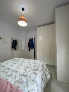 a white bedroom with a large bed and a light at Lungo mare holiday apartment for family in Vlorë