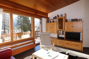 a living room with a large window and a television at Chesa Blais in Pontresina