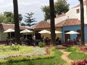 a restaurant with tables and umbrellas in a garden at Romantic patio-house for 2 in the old centre in La Orotava