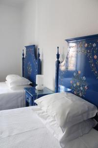 a bedroom with two beds and a blue headboard at Mont' Sobro House Rooms in Évora