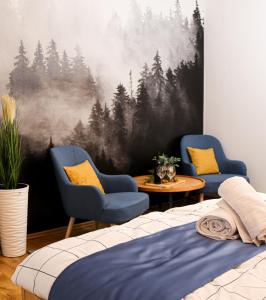 Villa Blue Apartman في سكسارد: غرفة نوم فيها كرسيين ودهان غابة