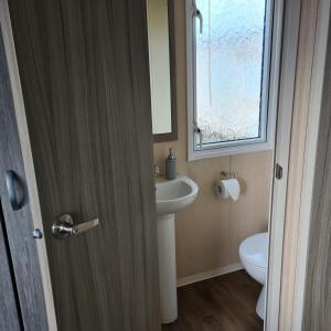 a bathroom with a sink and a toilet and a window at Oscars caravan in Abergele