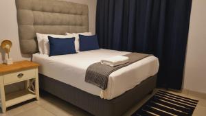 a bedroom with a bed with blue pillows and a table at Oceanic Unit 122 - Durban North Beach in Durban