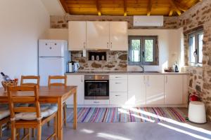 eine Küche mit weißen Geräten und einem Holztisch in der Unterkunft Messinian Stone House in Messini