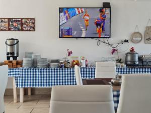 a television hanging on a wall above a dining room table at Kajaki i Rowery in Ruciane-Nida