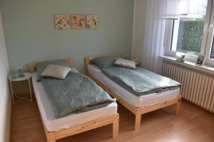 two twin beds in a room with two windows at FeWo am Naturschutzgebiet in Hiddenhausen