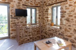 ein Wohnzimmer mit Steinwänden und einem Tisch in der Unterkunft Messinian Stone House in Messini