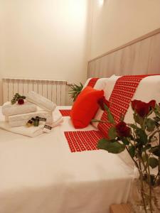 un letto bianco con cuscini rossi e bianchi e un vaso con fiori di Arcobaleno Rooms Venezia-Mestre a Mestre