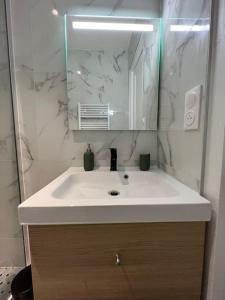 La salle de bains est pourvue d'un lavabo blanc et d'un miroir. dans l'établissement MIRA - Sublime apartment close to train station, à Corbeil-Essonnes