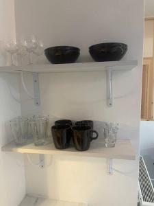 une étagère avec quatre bols et des verres dans l'établissement MIRA - Sublime apartment close to train station, à Corbeil-Essonnes