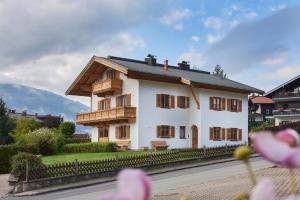 a large white house with a fence and flowers at AHORN7 in Reit im Winkl