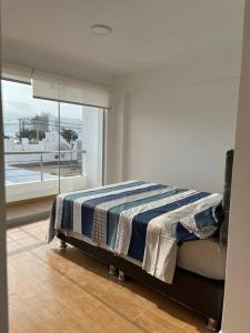 1 dormitorio con 1 cama con manta azul y blanca en SAN BARTOLO BEACH BUILDING, en San Bartolo