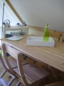 a wooden table with a green glass bottle on it at Ferme Rony Camp des Découvreurs in Saint-Nizier-du-Moucherotte