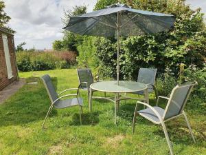 a table and chairs with an umbrella in the grass at Countryside 3 Bed Detached Cottage in Royal Wootton Bassett