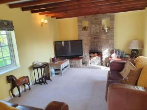 uma sala de estar com uma televisão e uma lareira de pedra em Countryside 3 Bed Detached Cottage em Royal Wootton Bassett
