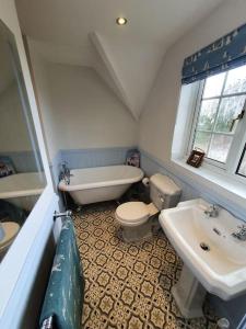 a bathroom with a tub and a toilet and a sink at Countryside 3 Bed Detached Cottage in Royal Wootton Bassett