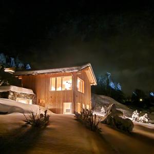 una cabaña de madera en la nieve por la noche en Chalet ski-in ski-out Nendaz, en Nendaz