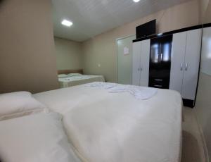 een slaapkamer met een wit bed en een zwarte koelkast bij Pousada Ritter in Bento Gonçalves