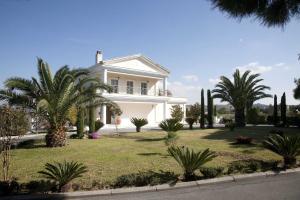 una casa blanca con palmeras y arbustos en Villa Elena, en Perea