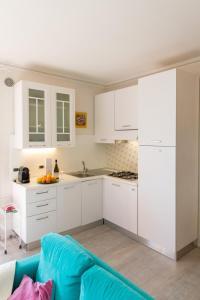 a kitchen with white cabinets and a blue couch at Blue Lake Home in Desenzano del Garda