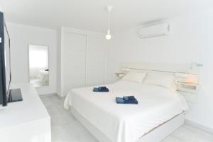 a white bedroom with a white bed with two towels on it at Luxury Buenavista Famara in Famara