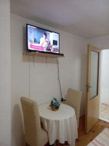 a room with a table and a television on a wall at Soba Dujaković in Banja Vrućica