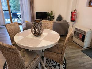 een tafel met stoelen en een vaas in de woonkamer bij Rustig gelegen chalet Kapeki met tuin aan het water in Geel