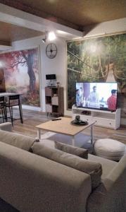a living room with a couch and a large screen tv at Au bord de la Moselle in Ramonchamp