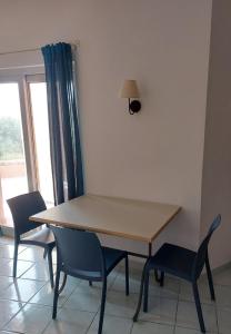 mesa y sillas en una habitación con ventana en Appartamento Calarossa Sardegna CasaRosa, en Isola Rossa