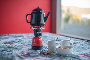 a coffee maker on a table with two cups of coffee at Donkieshoek Accommodation & Campsite, Calvinia in Calvinia