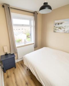 um quarto com uma cama branca e uma janela em Highgate Beach House em Cleethorpes