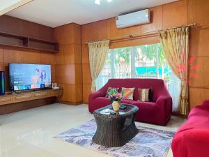a living room with a red couch and a tv at Mantra Pattaya Pool Villa-Pool with Jacuzzi in Pattaya-Pet-Friendly in Jomtien Beach