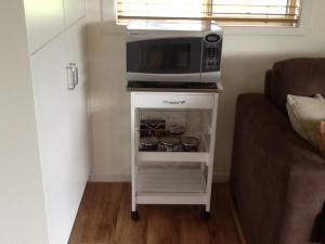 a microwave on a white cart with pots and pans at Glen Waverly Farmstay in Glen Innes