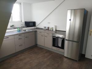 eine Küche mit einem Kühlschrank aus Edelstahl und einer Spüle in der Unterkunft Nilos Apartment in Diez