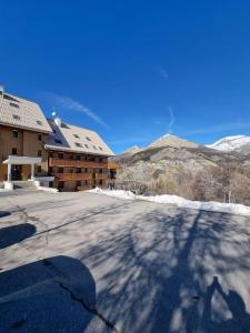 una sombra de un edificio en una calle cubierta de nieve en Studio au pied des pistes en Allos