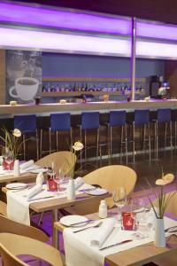 a dining room with tables and chairs and purple lighting at IntercityHotel Bonn City in Bonn +18 photos